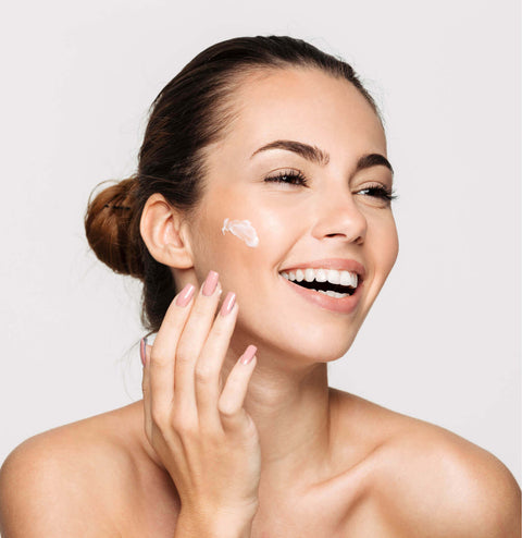 Image of a woman highlighting her eyelashes and at the same time applying cream to her face