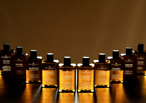 Row of Philip Martin's hair care products on a reflective surface with a warm glow.